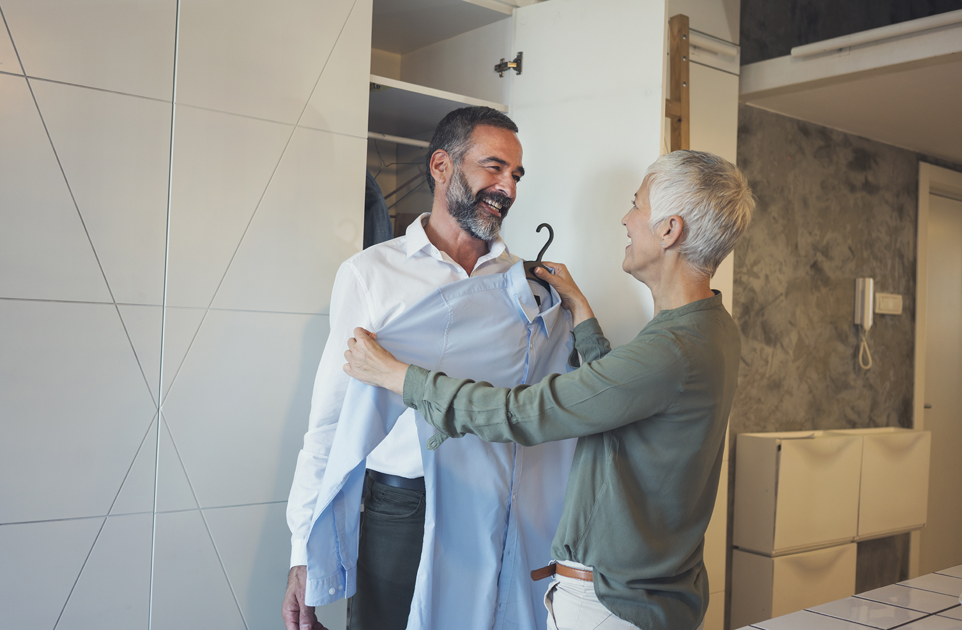 Beautiful mature couple at home preparing for work, choosing shirt